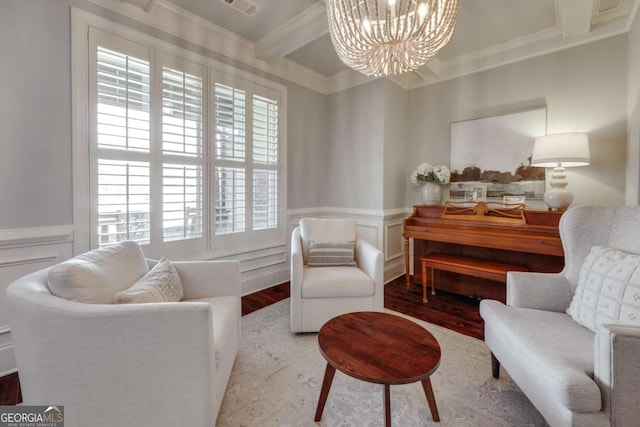 living area with a wainscoted wall, beamed ceiling, an inviting chandelier, and crown molding