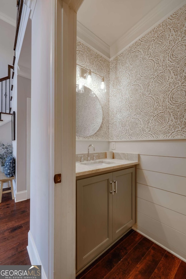 bathroom with baseboards, wood finished floors, vanity, and crown molding