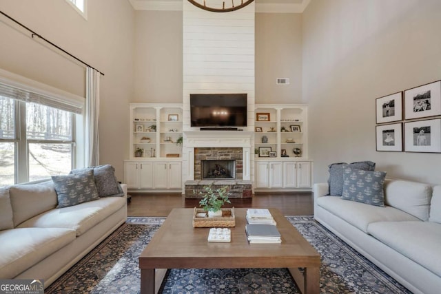 living room featuring visible vents, dark wood finished floors, a stone fireplace, and a high ceiling