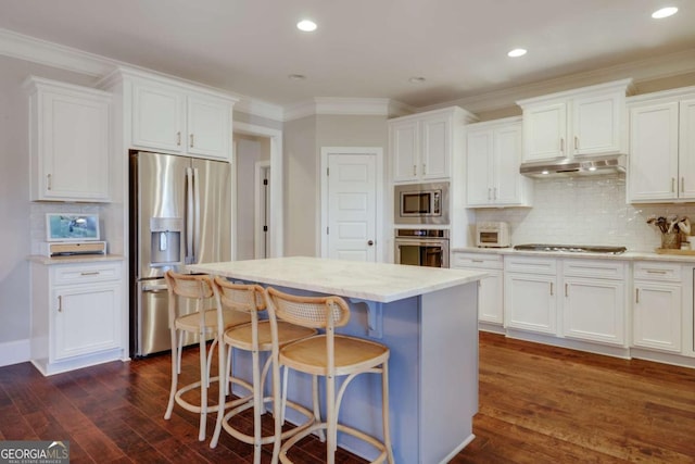 kitchen featuring under cabinet range hood, stainless steel appliances, white cabinets, a center island, and dark wood-style floors