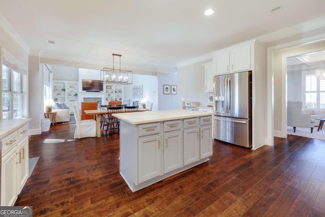 kitchen with stainless steel fridge, white cabinetry, light countertops, and a center island