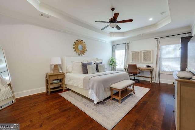 bedroom with a raised ceiling, visible vents, dark wood finished floors, and multiple windows