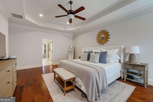 bedroom featuring dark wood-style floors, a tray ceiling, and visible vents