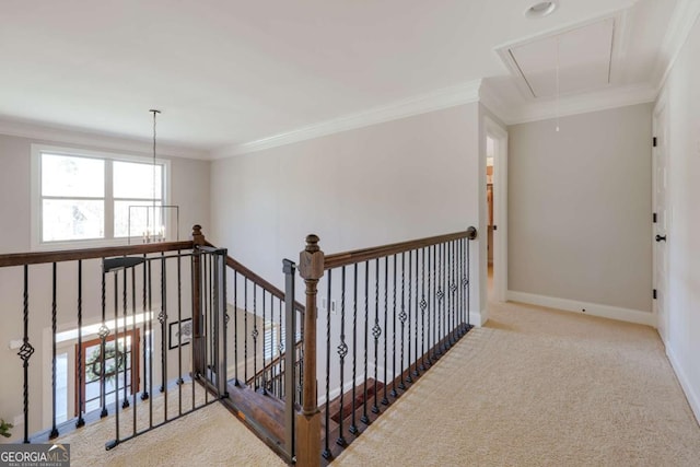 corridor featuring attic access, baseboards, light colored carpet, ornamental molding, and an upstairs landing