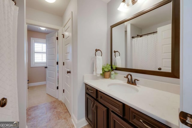 bathroom with stone finish floor, vanity, and baseboards