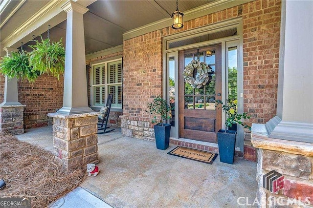 property entrance featuring covered porch and brick siding