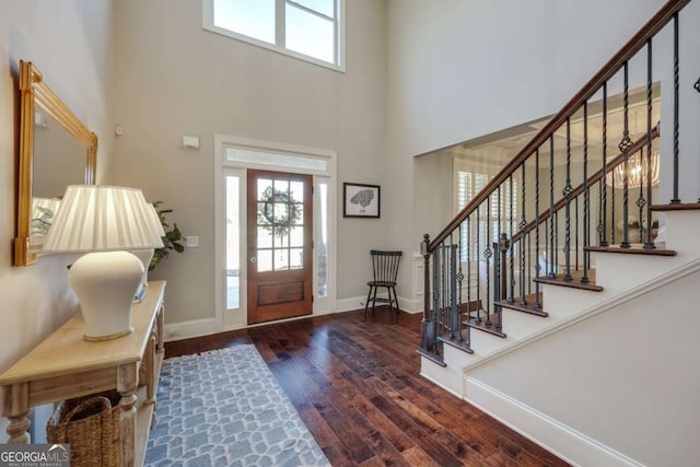 foyer featuring stairs, dark wood-type flooring, a high ceiling, and baseboards