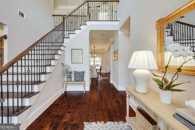 entrance foyer with a high ceiling, visible vents, baseboards, ornamental molding, and dark wood finished floors