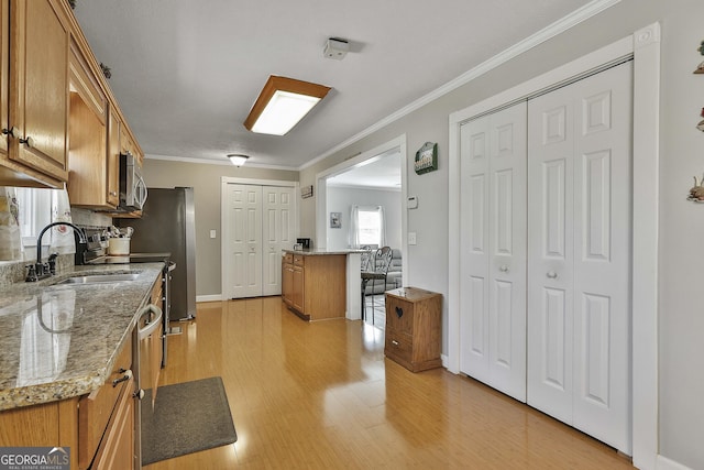 kitchen featuring light wood-type flooring, stainless steel microwave, brown cabinetry, and a sink