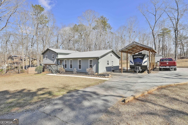 view of front of home with metal roof, aphalt driveway, a carport, and a front yard