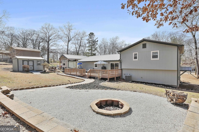 rear view of house with an outbuilding, a deck, cooling unit, a fire pit, and a shed