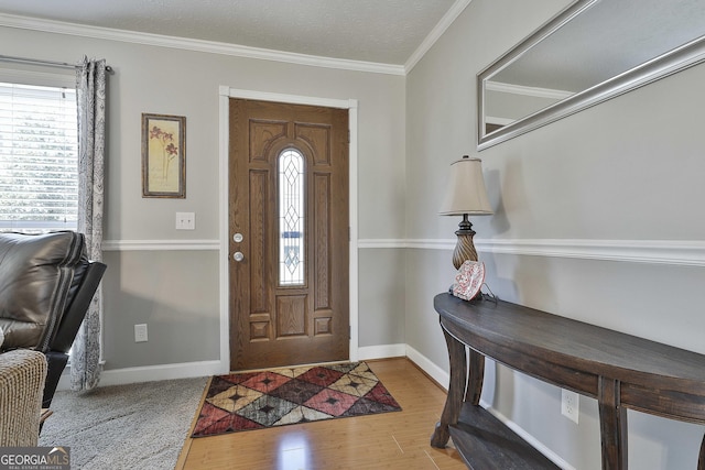 foyer entrance featuring baseboards, wood finished floors, and crown molding