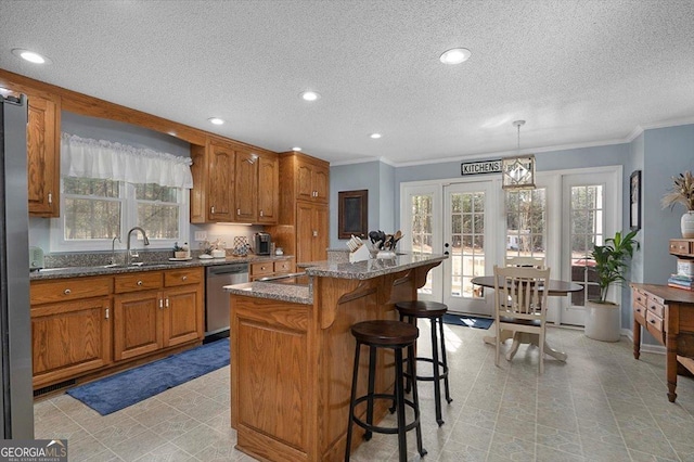 kitchen with brown cabinets, stainless steel dishwasher, a sink, a breakfast bar, and a center island