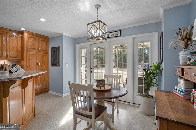 dining room with a textured ceiling, crown molding, baseboards, an inviting chandelier, and french doors