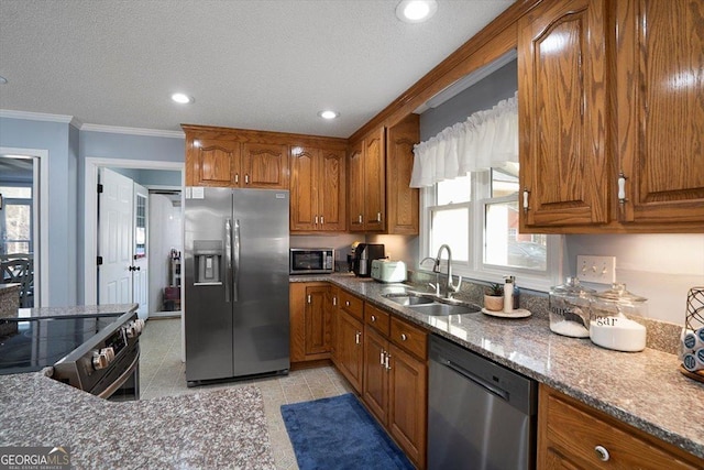 kitchen featuring a wealth of natural light, appliances with stainless steel finishes, brown cabinets, ornamental molding, and a sink