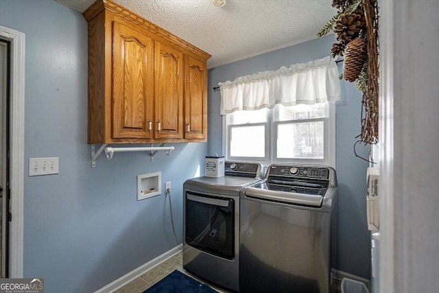 laundry room with a textured ceiling, cabinet space, washing machine and clothes dryer, and baseboards