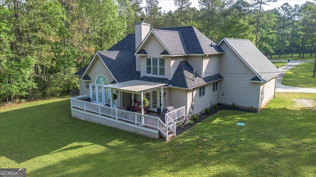 rear view of property featuring a chimney, french doors, a shingled roof, and a lawn