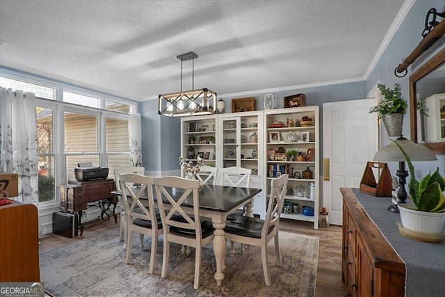 dining space with a textured ceiling, crown molding, a notable chandelier, and dark wood-type flooring