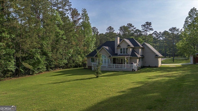 rear view of property with a lawn, a chimney, and covered porch
