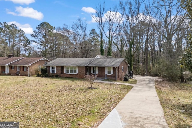 view of front of home featuring concrete driveway, brick siding, and a front lawn