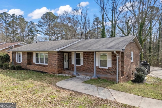 ranch-style home with roof with shingles, a porch, a front lawn, and brick siding