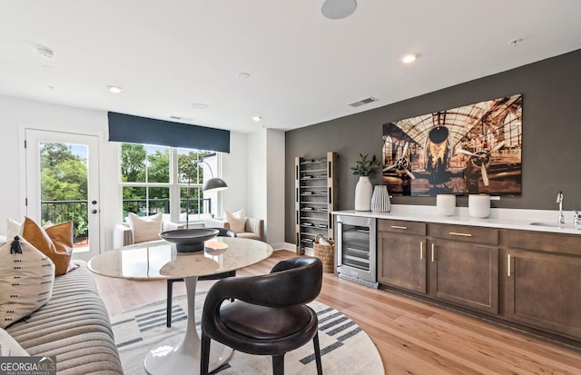 dining space featuring beverage cooler, light wood finished floors, recessed lighting, and a dry bar