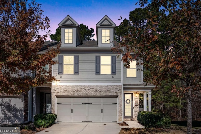 view of front of property with driveway, an attached garage, and brick siding