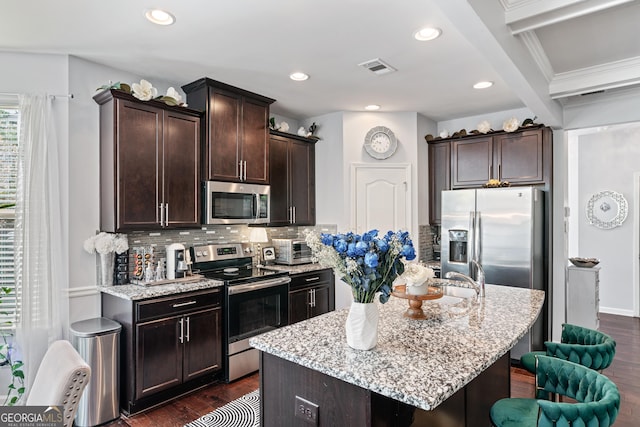 kitchen featuring stainless steel appliances, dark brown cabinets, backsplash, and dark wood finished floors