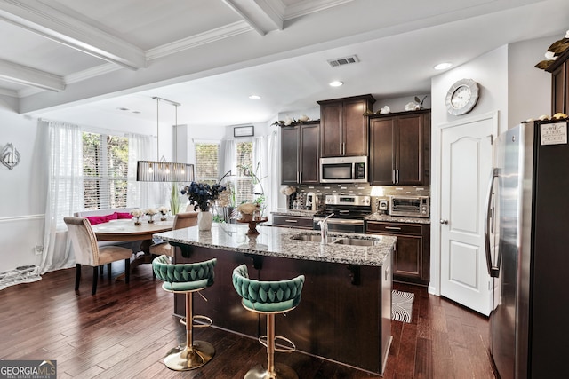 kitchen with light stone countertops, dark wood-style flooring, stainless steel appliances, and beam ceiling