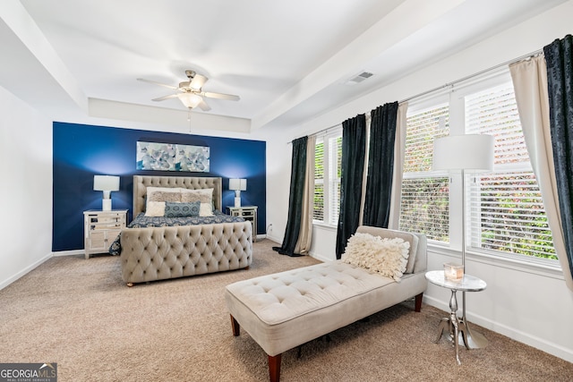 carpeted bedroom featuring a tray ceiling, a ceiling fan, visible vents, and baseboards