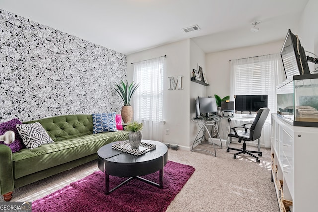 carpeted home office with baseboards, an accent wall, and visible vents