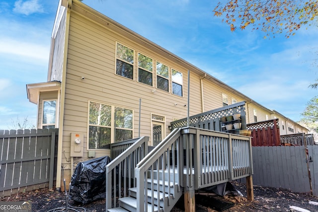 rear view of house featuring fence and a wooden deck