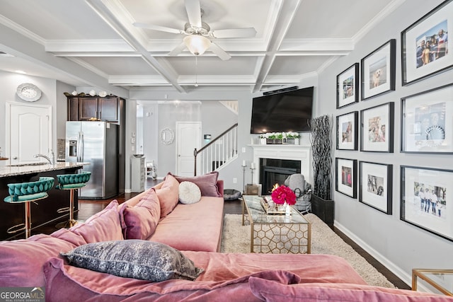 living area featuring a fireplace, baseboards, coffered ceiling, and wood finished floors