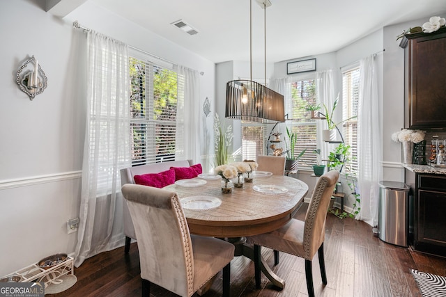 dining space with dark wood-style flooring, visible vents, and baseboards