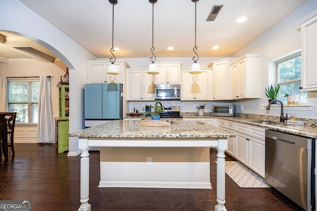 kitchen with appliances with stainless steel finishes, decorative light fixtures, and a kitchen island