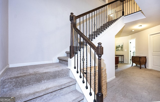 staircase with carpet flooring, a towering ceiling, and baseboards