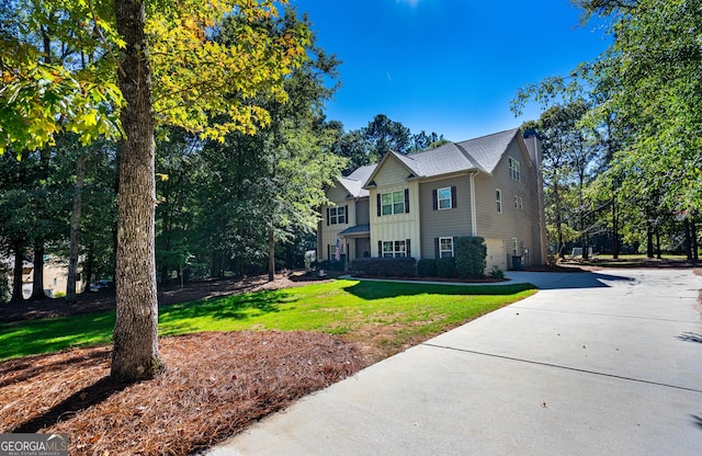 view of front facade featuring a chimney, concrete driveway, and a front yard