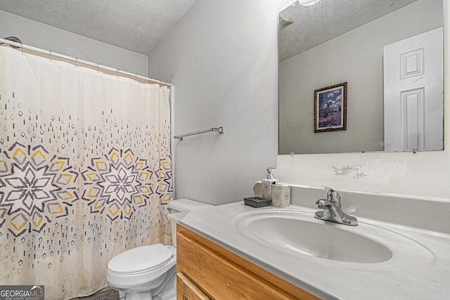 full bathroom with a textured ceiling, toilet, and vanity