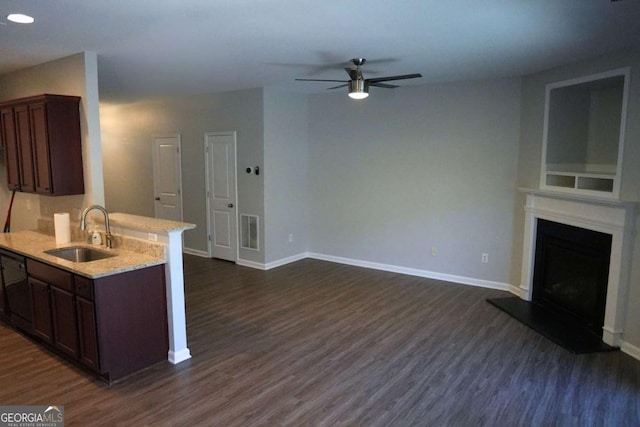 kitchen with baseboards, visible vents, a fireplace with raised hearth, dark wood-style flooring, and a sink