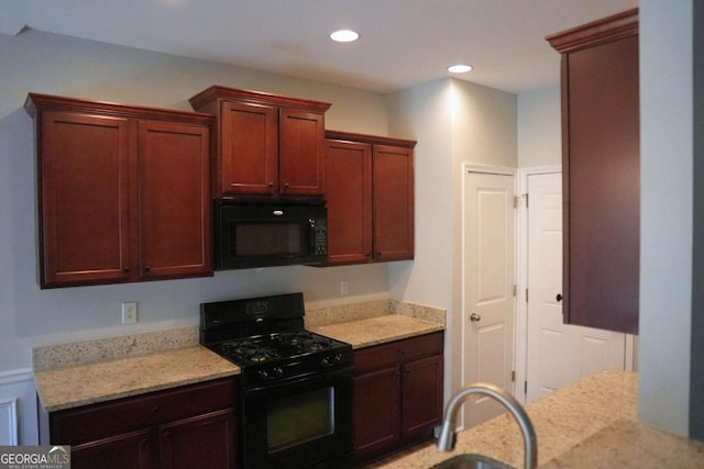 kitchen featuring light stone counters, dark brown cabinets, black appliances, a sink, and recessed lighting