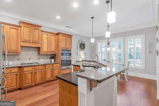 7524 Portbury Park Ln, Suwanee, GA 30024 - kitchen featuring dark countertops, brown cabinets, a kitchen island with sink, pendant lighting, and a sink
