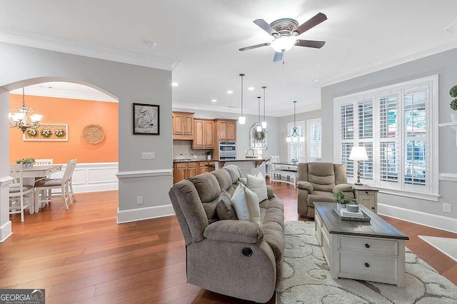 7524 Portbury Park Ln, Suwanee, GA 30024 - living room with arched walkways, recessed lighting, ceiling fan with notable chandelier, ornamental molding, and light wood-type flooring