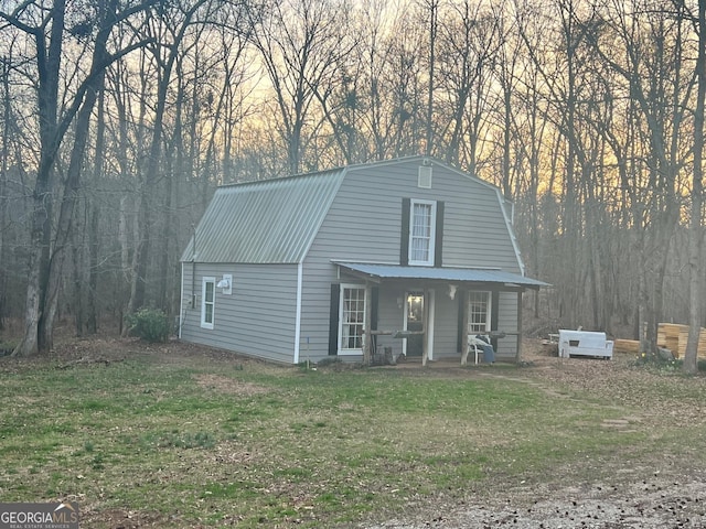 colonial inspired home featuring metal roof, a front yard, a porch, and a gambrel roof