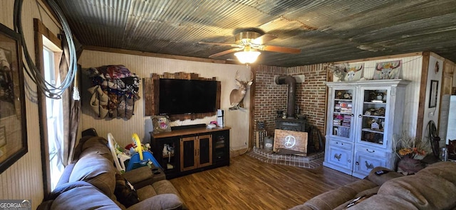 living area featuring a wood stove, ceiling fan, and wood finished floors