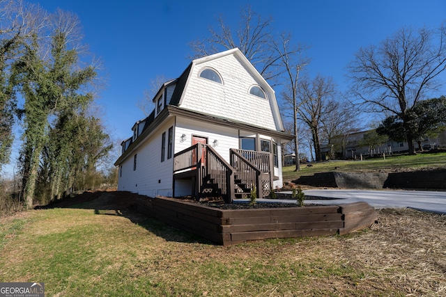 exterior space with a lawn, stairway, a wooden deck, and a gambrel roof