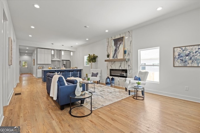 living room with recessed lighting, visible vents, a high end fireplace, light wood-type flooring, and baseboards