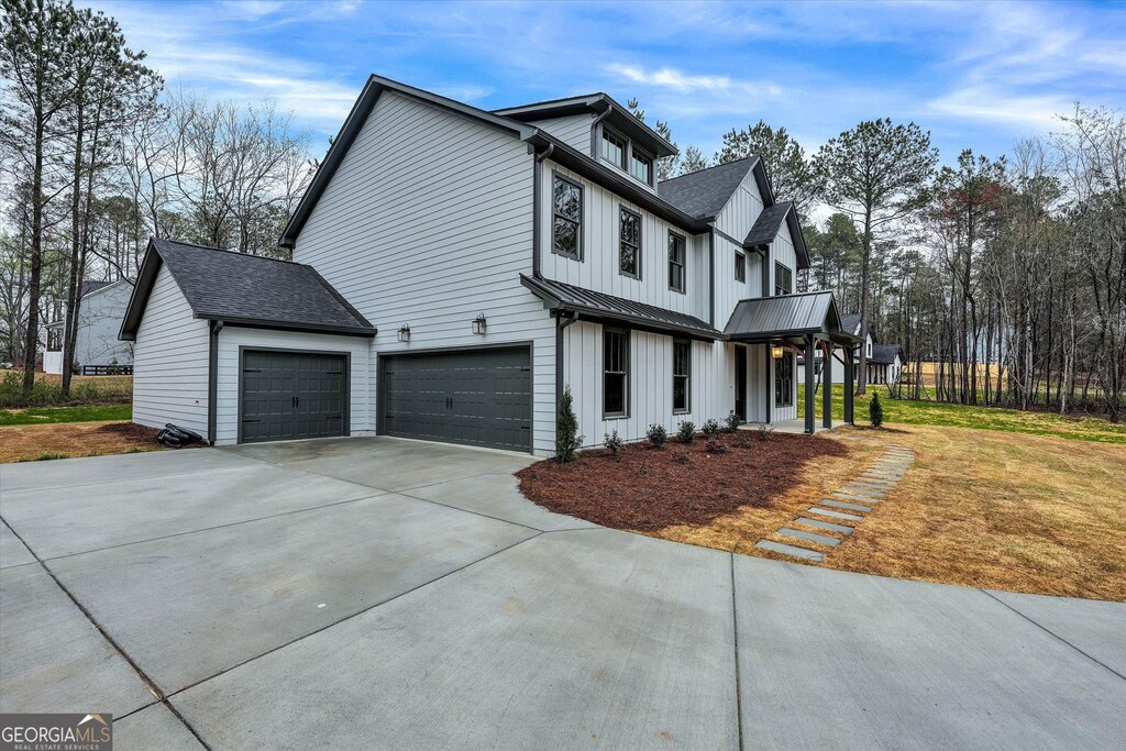 modern inspired farmhouse with metal roof, a garage, board and batten siding, a standing seam roof, and a front yard