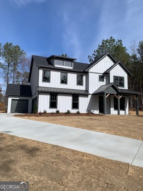 modern inspired farmhouse with metal roof, a garage, board and batten siding, a standing seam roof, and a front yard