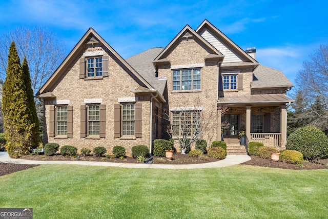 view of front of property with covered porch, brick siding, and a front lawn