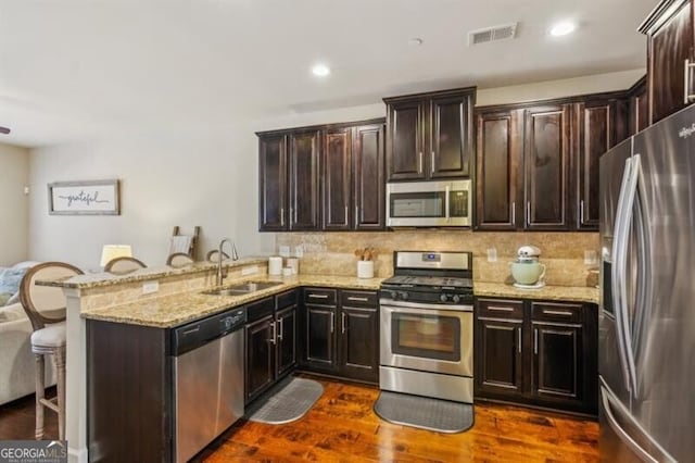 7420 Glisten Ave, Sandy Springs, GA 30328 - kitchen featuring light stone counters, appliances with stainless steel finishes, a kitchen breakfast bar, a peninsula, and a sink